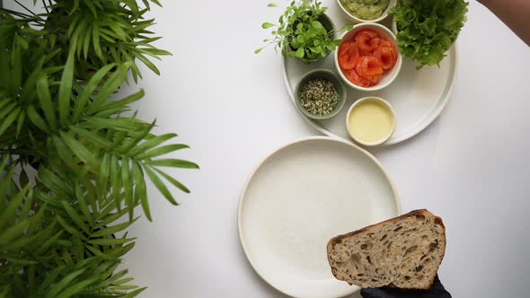 Hands in Black Gloves Put Green Guacamole on Bread Slice