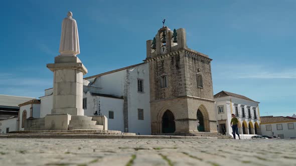 Girl Tourist Walks Through the Square of the Ancient Church of Santa Maria Near the Monument Bishop