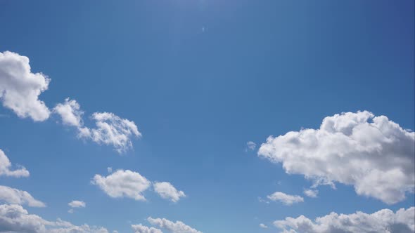 Time lapse of white cumulus clouds flying in the blue sky.