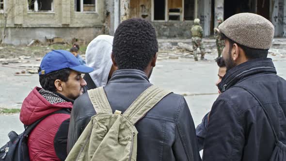 Homeless Refugees Talking before Destroyed Building