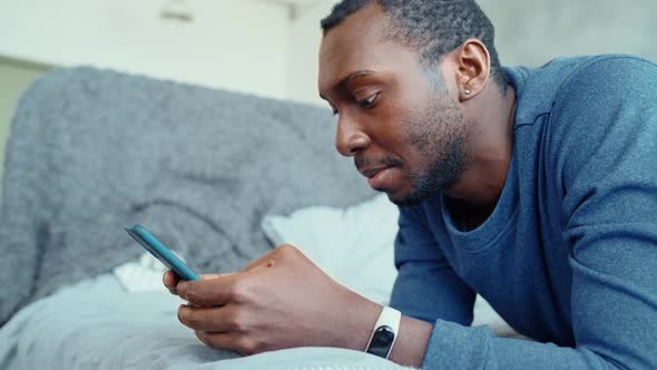 Front View of a Guy Using a Mobile Phone in the Bedroom at Home