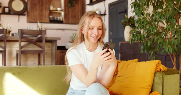 Charming young woman using smartphone, texting sharing messages on social media. 