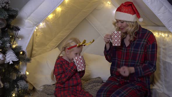 Mom and Child Drink Cocoa at Home in the Christmas Interior