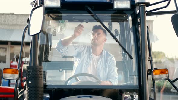 Young Handsome Man Inspects Tractors Cabin