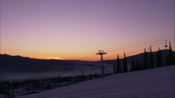 Silhouette of Poma Lift with Moving Cabins Over Snowy Hill