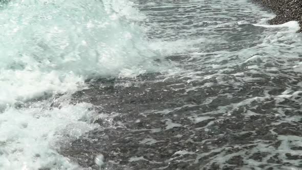 Waves hit the shore at beach of Kalamata, Peloponnese, Greece, slow motion tilt reveal shot