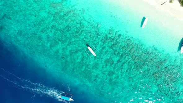 Tropical vacation background. Boats floating in the crystal clear waters of Indonesia sea. Aerial hi