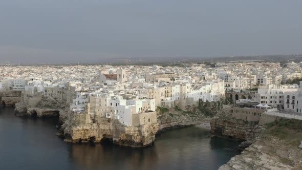 Aerial forward view of perched tip of Polignano a Mare. Italy. Daylight