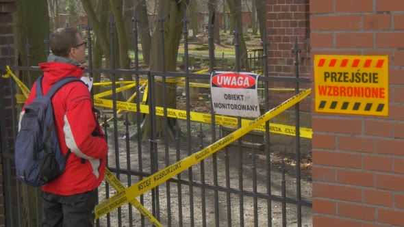 Backpacker Man is Standing in Front of Fence