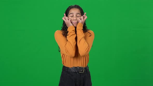 Excited Teen African American Girl Crossing Fingers Closing Eyes Standing at Chromakey Background