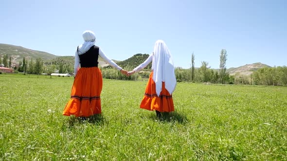 Women In Traditional Dress Walking In The Meadow In Village