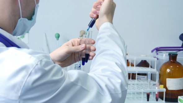 Rear View Of Male Scientist Doctor Injecting Chemicals Into Test Tubes