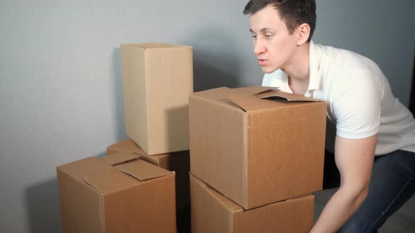 Young Delivery Service Man Takes a Lot of Cardboard Box and Heavy Boxes Falling