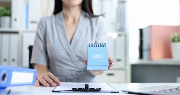 Businesswoman Sitting at Table and Holding Loose Leaf Paper Calendar for 2022 Closeup Movie Slow