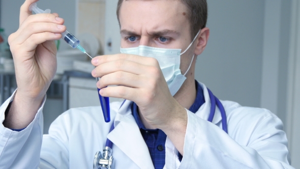 Portrait Of Young Male Caucasian Doctor Pouring a Blue Liquid From a Syringe