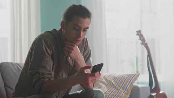 Young Man Relaxes Using Smartphone