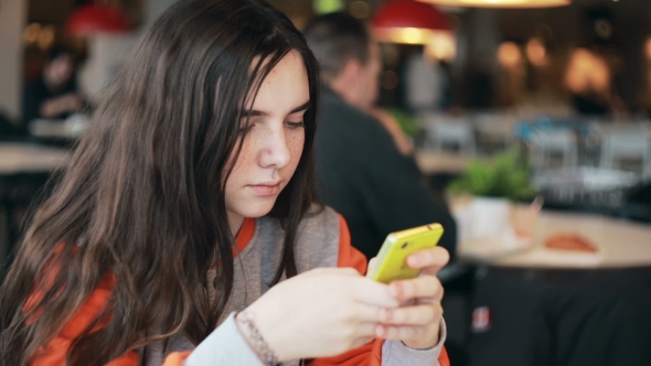 Teenage Girl Using Smartphone In Cafe. 