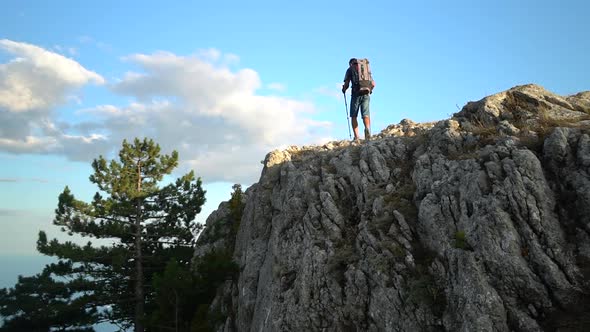 Young Male Athlete is Hiking on Rocky Mountain Under Blue Sky on Autumn Spbd