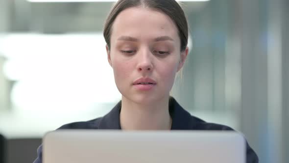 Portrait of Young Businesswoman Looking at Camera while working on Laptop 