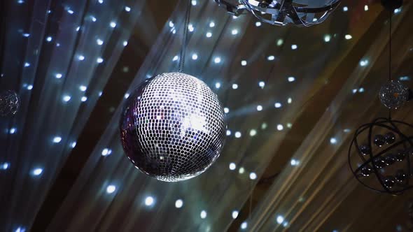 Night club ceiling with mirror ball and lights. Silver disco ball spinning against beautiful shining