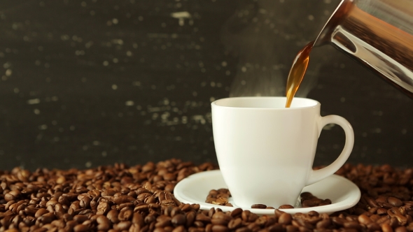 Pouring Coffee In Cup Surrounded By Coffee Beans