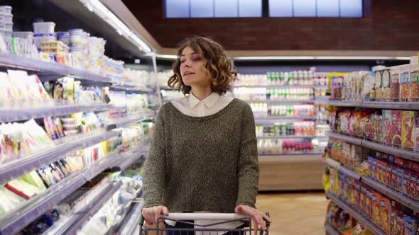 Portrait of Happy Relaxful Woman with Curly Hair Went Shopping with Trolley Cart Walk By a Row and