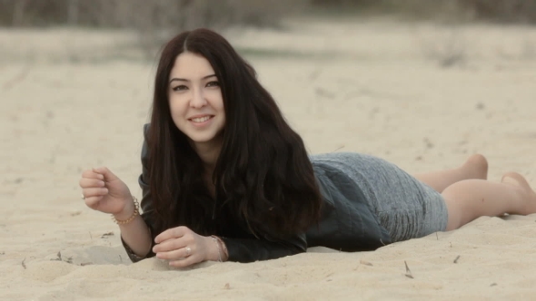 Cute Brunette Lies On Sand And Contorts Emotions