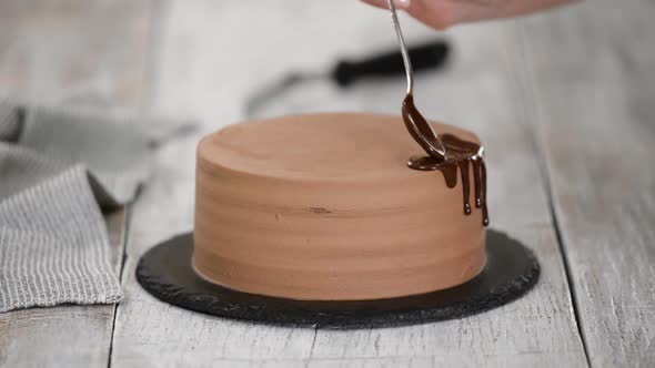 Glazing chocolate cake with melted chocolate. Woman pouring chocolate over cake