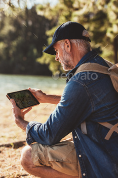 ing by a lake and using digital tab in the forest for navigation.