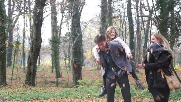 Woman Throwing Leaves At Her Daughter And Husband In The Park