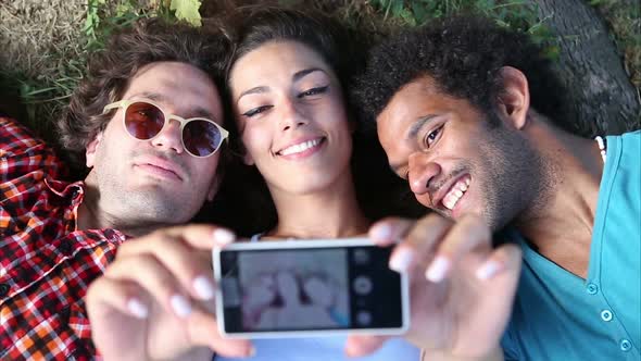 Three Young Adults Taking A Selfie Lying On The Grass 2