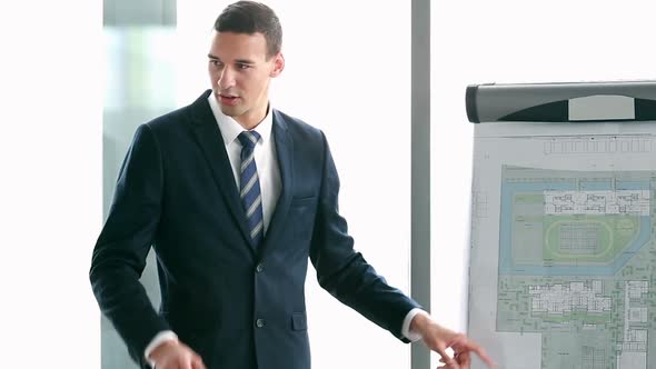 Young Businessman Pointing At Flipchart During Presentation