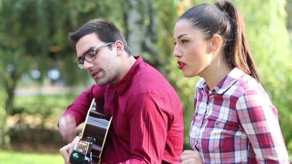 Young Couple Playing Guitar And Singing In Park 3