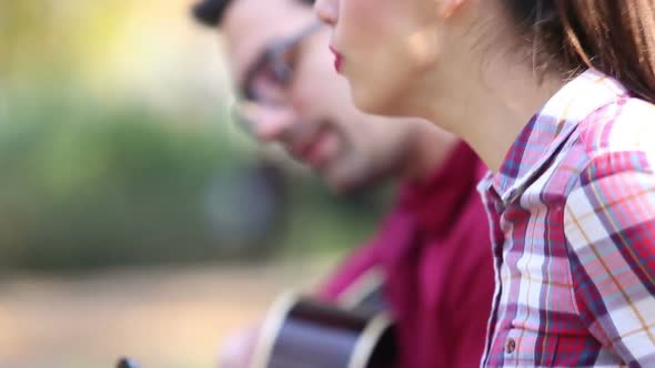Young Couple Playing Guitar And Singing In Park 6