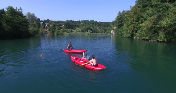 Four Friends Having Fun Paddling Canoe And Jumping Into River 1