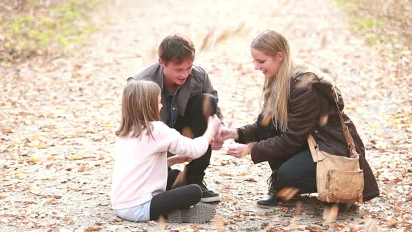 Young Family Sitting On Pathway In Park And Playing Games 1