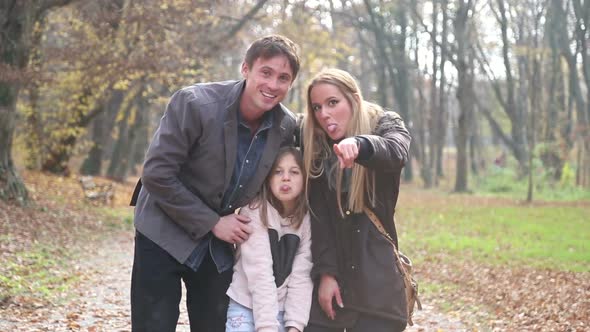 Young Family Waving At Camera In The Park 1