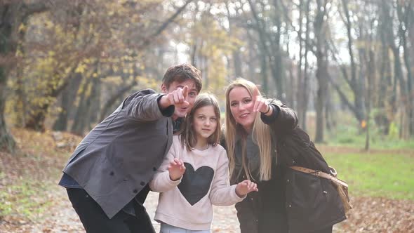 Young Family Waving At Camera In The Park 2