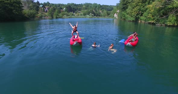 Young Friends Having Fun Paddling Canoe And Jumping Into River 1