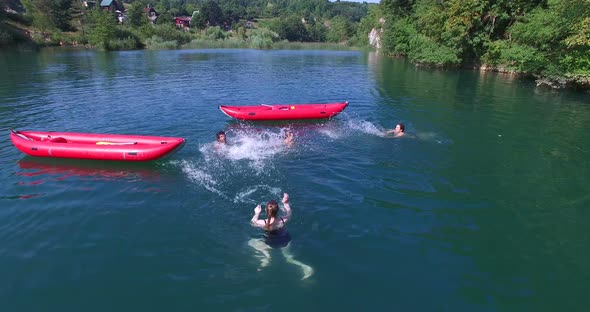 Young Friends Having Fun Swimming In River And Splashing Each Other With Water