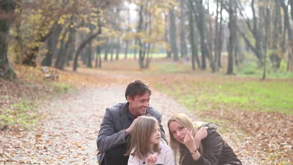 Parents Having Fun With Daughter In The Park, Beckoning At Camera