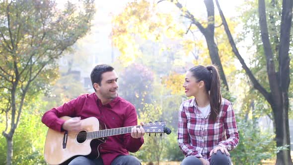 Young Man And Women Playing Guitar And Singing In Park 2