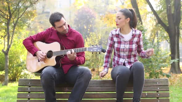 Young Man And Women Playing Guitar And Singing In Park 4