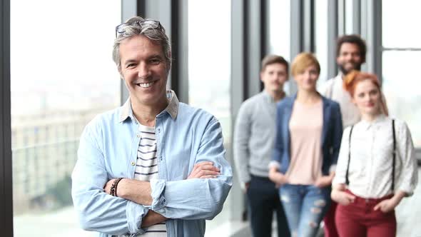 Portrait Of Creative Director Smiling, Colleagues In Background