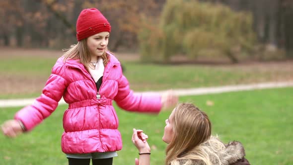 Girl Explaining Game To Her Mom In Park, Dad Coming And Hugging Her