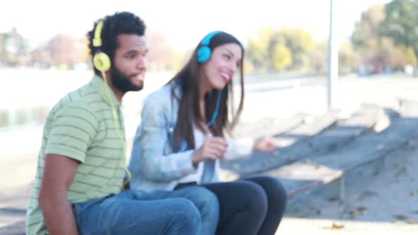 Couple Having Fun Listening To Music On Headphones At The Park 1