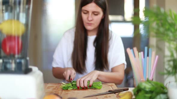 Young Woman Cutting Spinach On Wooden Board 1