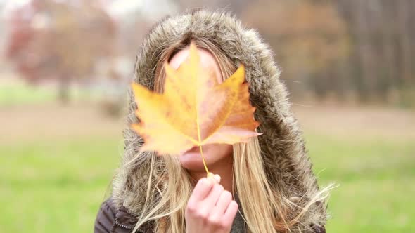 Young Woman Holding Leaf In Front Of The Face, Moving It And Making Funny Faces 2