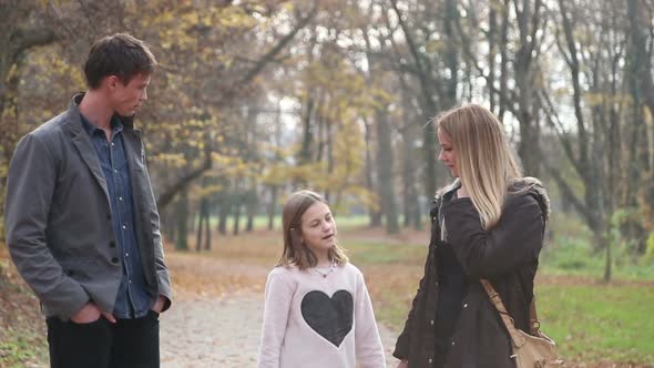 Girl Talking With Parents While They Walking In The Park