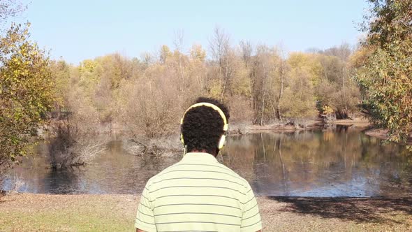 Back View Of Man With Headphones Listening To Music By The Lake 2